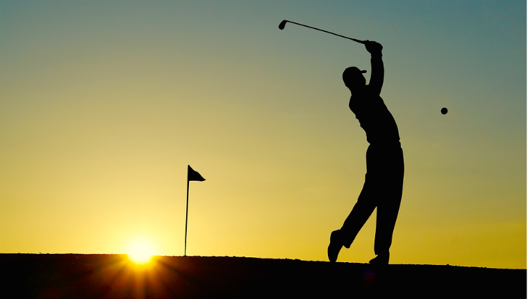 man playing golf at sunset